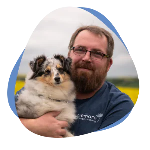 Mann mit Bart und Hund auf dem Arm